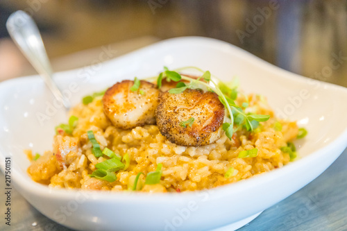 Tasty risotto with Gulf Shrimp, crawfish tails, seared scallops, fresh herbs vegetables on a white plate