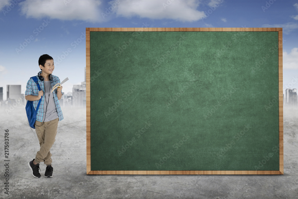 Asian preteen student stands near a chalkboard Asian preteen student stands near a chalkboard