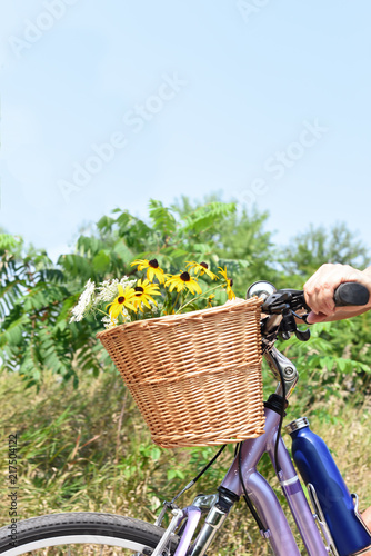 wicker basket full of flowers on bike handlebars in summer
