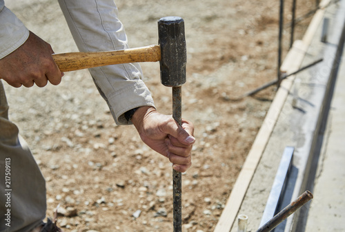 Fotografija Man using a sledge hammer to fasten down a form stake