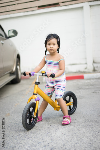 Little girl learns to riding balance bike in car park