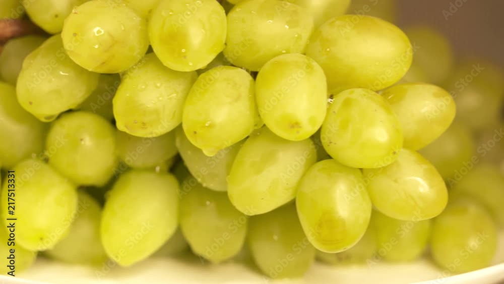 Bunch of white grapes turning around. Wet green grape with water drops close-up Bunch of white grapes turning around. Wet green grape with water drops close-up