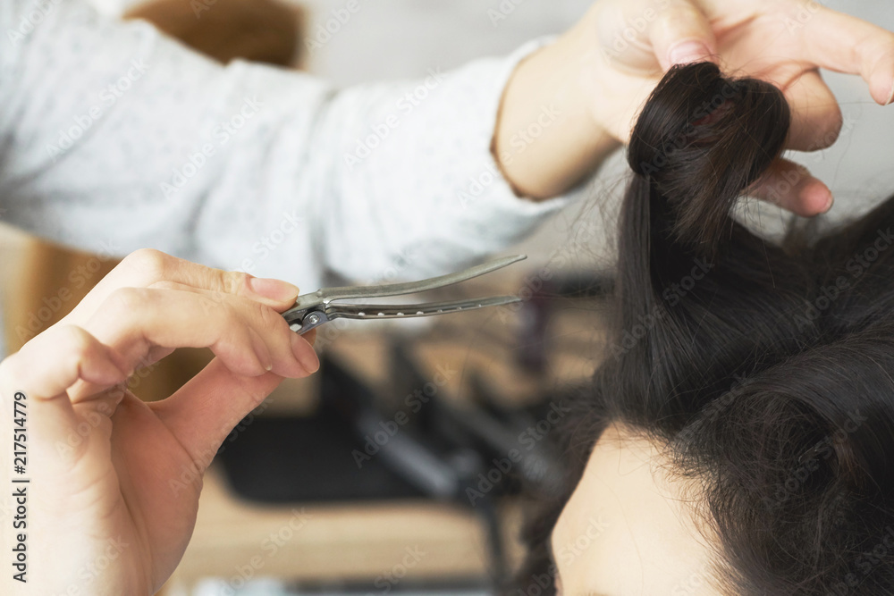 Fototapeta premium Closeup view of the hairstylist hand combing a new hairstyle on a customer head in hair salon.
