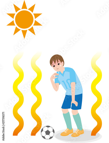 酷暑の中でサッカーする男の子.熱中症の危険.