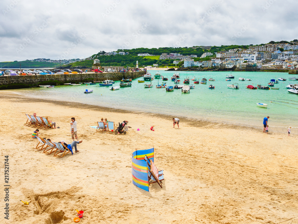 Families enjoying the summer at St Ives Beach, with the attractive bay and blue sea behind them.