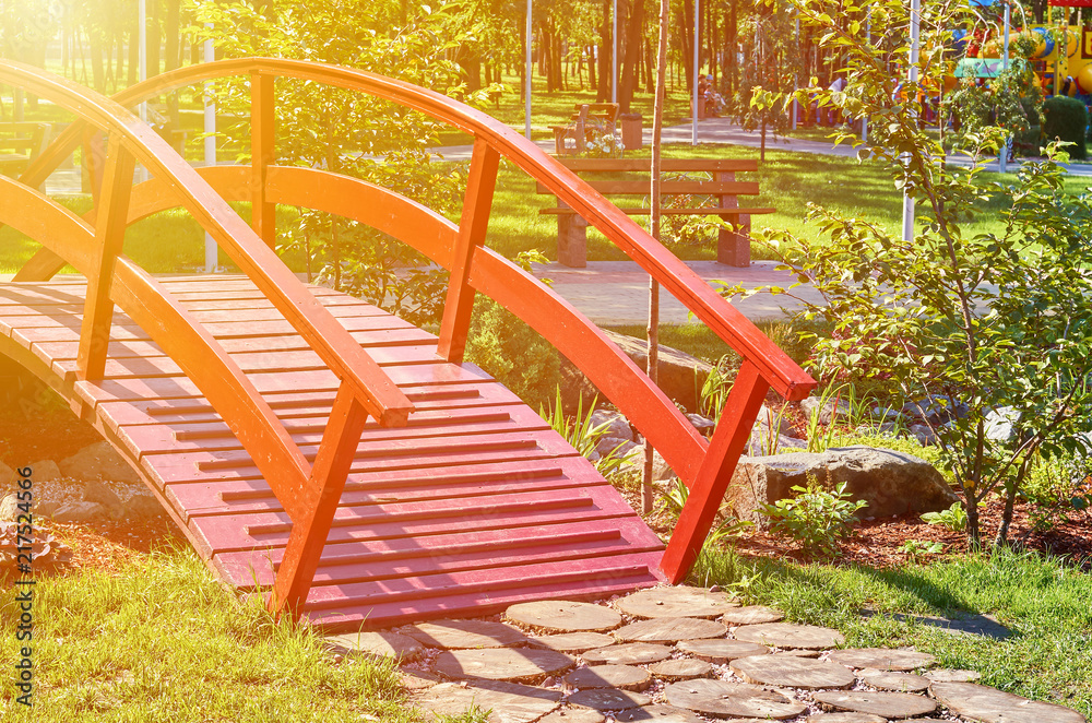 wooden red decorative bridge across the pond, sunlight effect wooden red decorative bridge across the pond, sunlight effect