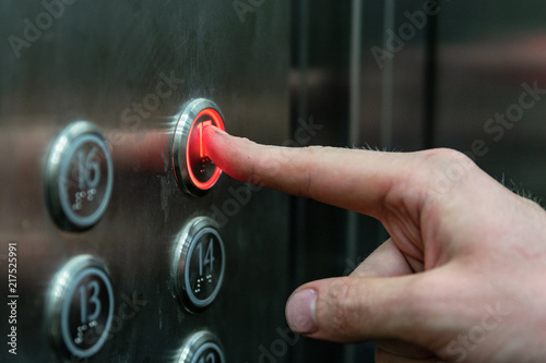 the man presses the elevator button with the red light.