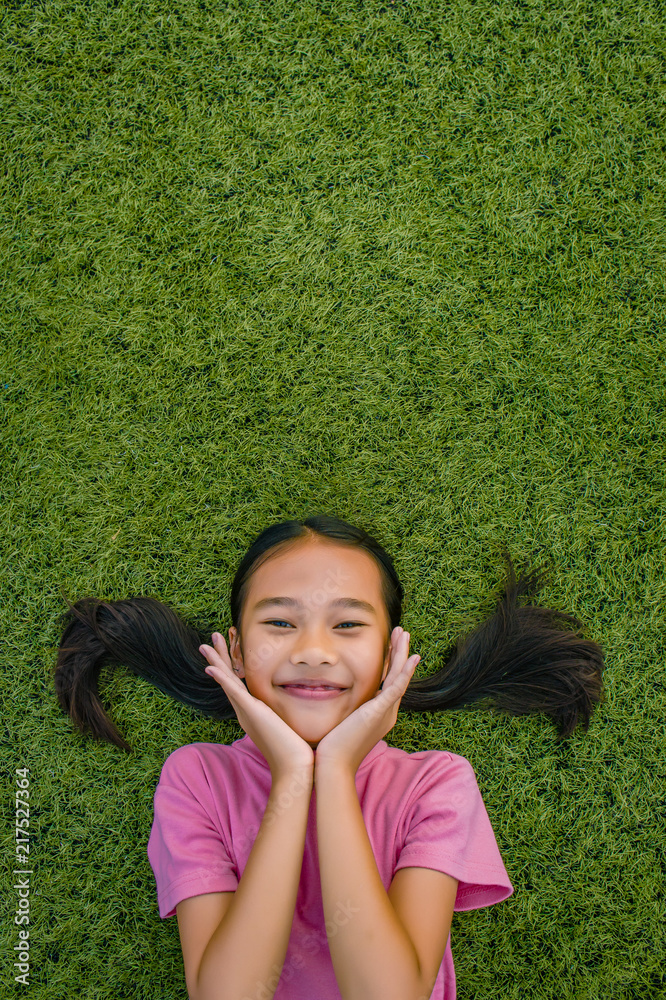 kid asian girl's lie leisurely on the Lawn floor and smile looking at kid asian girl's lie leisurely on the Lawn floor and smile looking at