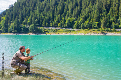 happy father and son fishing together on a mountain lake