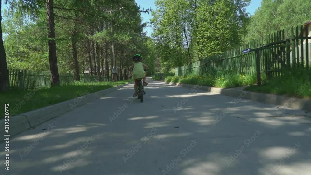Little boy in helmet riding bicycle in suburbs in sunny day. Little boy in helmet riding bicycle in suburbs in sunny day.