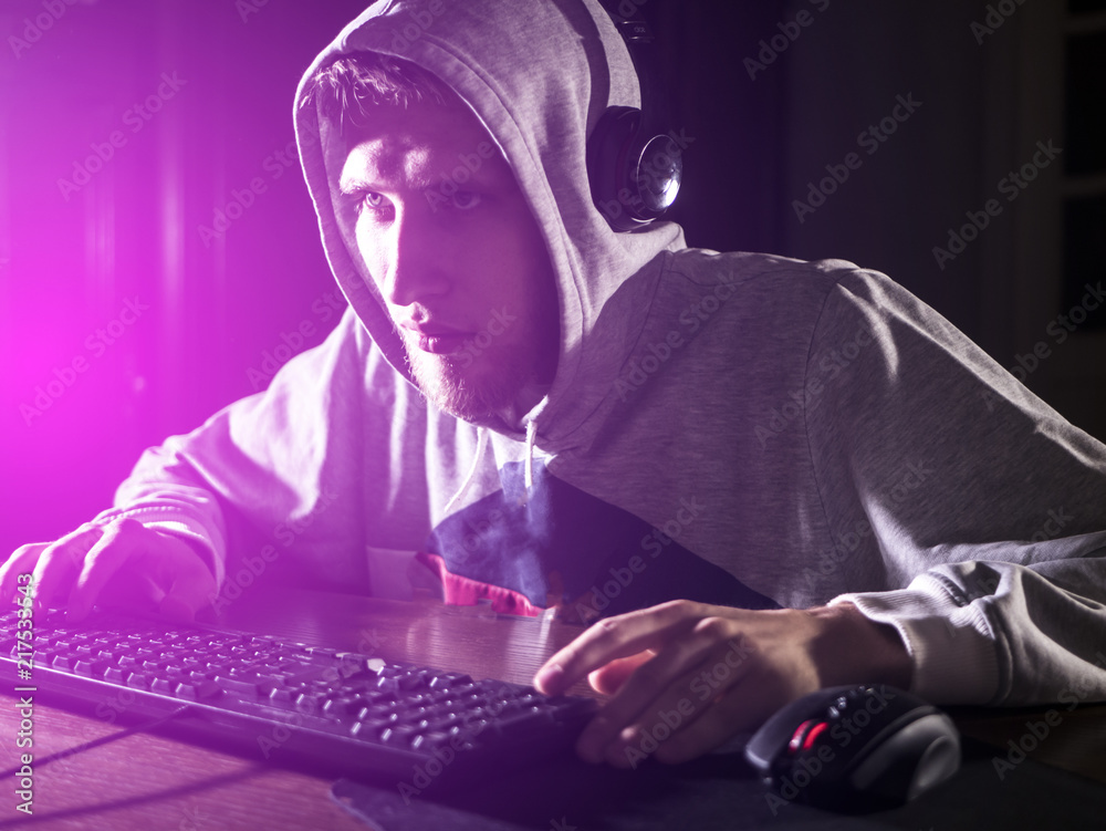 young male video game addict in the hood playing shooters in the night young male video game addict in the hood playing shooters in the night