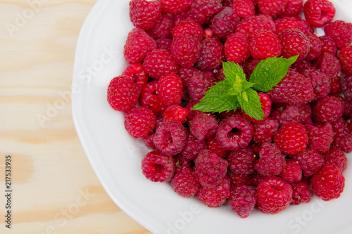 Red and delicious raspberries with mint in a white bowl