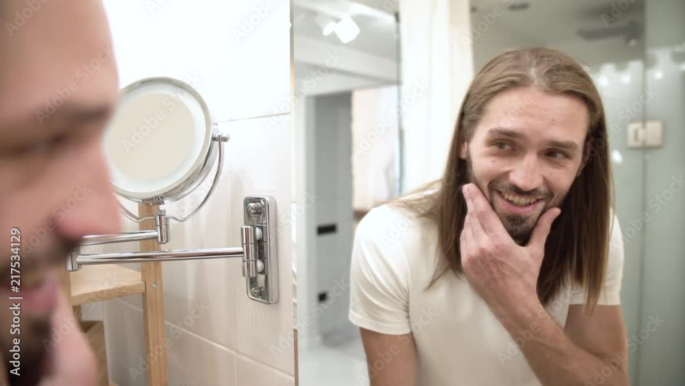 Bathroom. Man Looking In Mirror And Touching Face Bathroom. Man Looking In Mirror And Touching Face