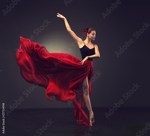 Ballerina. Young graceful woman ballet dancer, dressed in professional outfit, shoes and red weightless skirt is demonstrating dancing skill. 
Beauty of classic ballet dance. 
