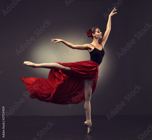 Ballerina. Young graceful woman ballet dancer, dressed in professional outfit, shoes and red weightless skirt is demonstrating dancing skill. 
Beauty of classic ballet dance. 
