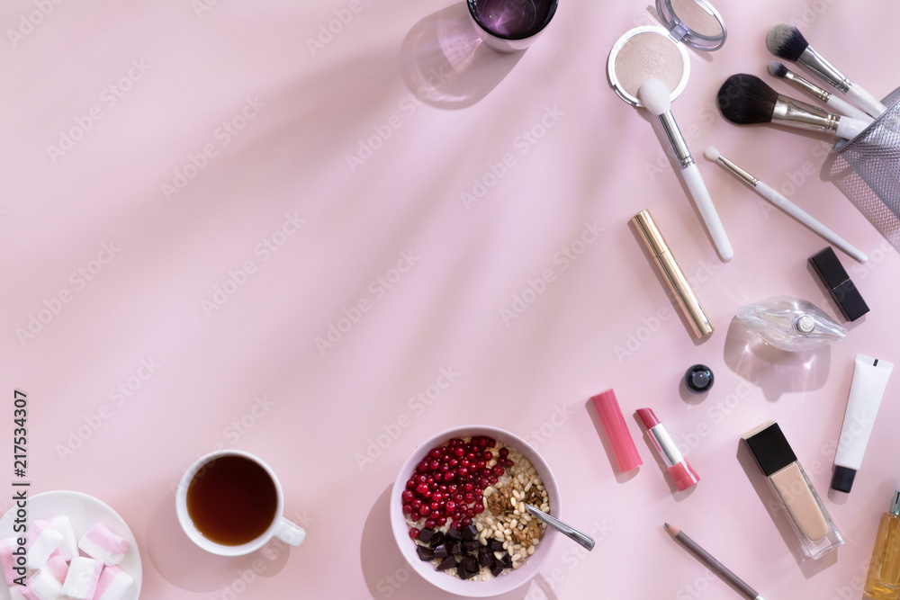 Fototapeta Top view of elegant woman make up table with pink and white accents and shadows on background, female morning with healthy breakfast oat flakes with berries, flat lay and copy space