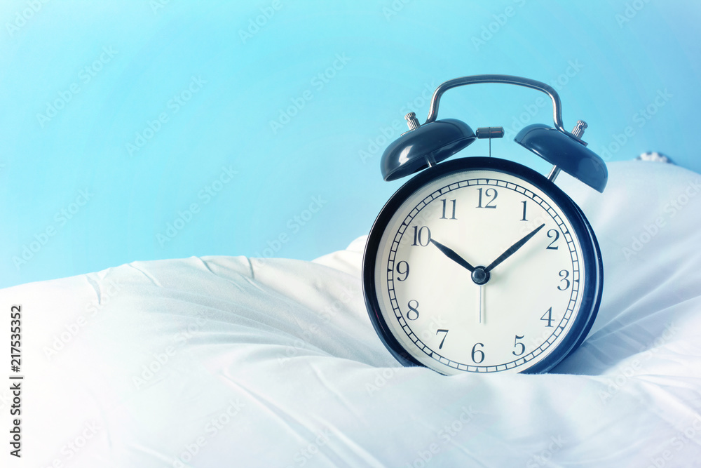 Fotografie Alarm clock on the pillows. Advertizing concept, copy space