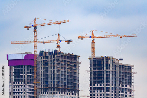Three orange tower cranes build a modern panel houses