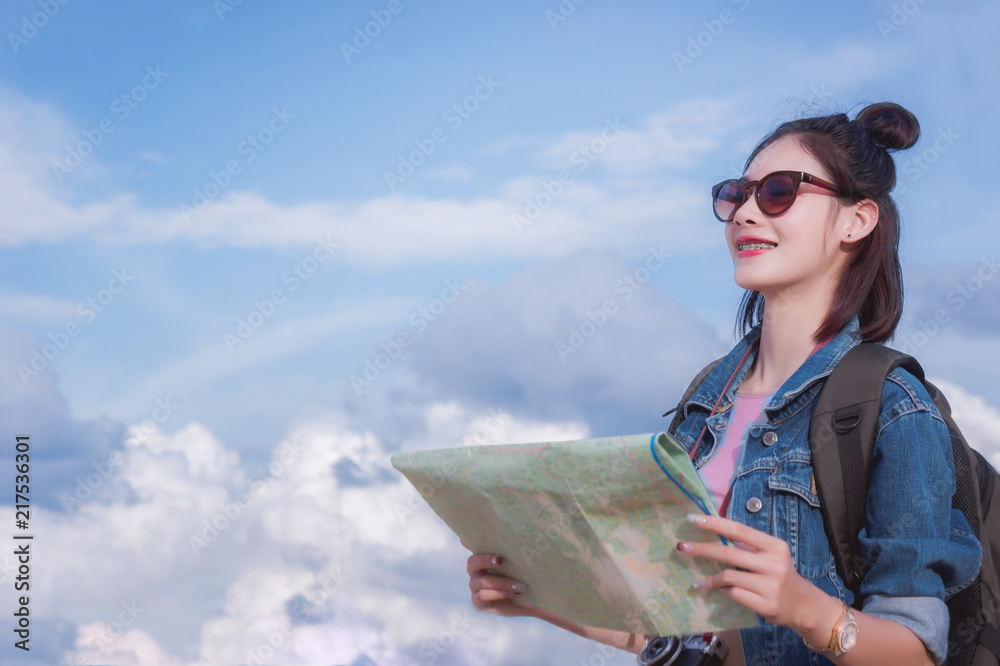 girl's looking at destination and hold a map on street .
