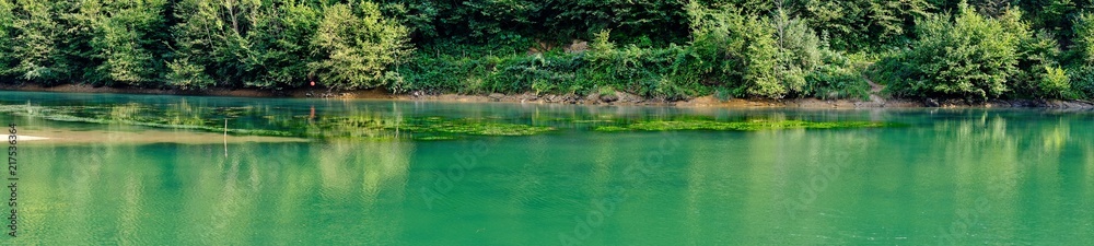 Scorcio di un Lago di montagna verde smeraldo circondato da alberi. Vista panoramica