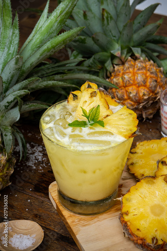 Pineapple juice and pineapple slices cut into pieces on a wooden table. Healthy wood fiber helps to reduce food. Pineapple juice Contains fresh milk, nectar and salt.