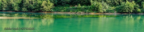 Scorcio di un Lago di montagna verde smeraldo circondato da alberi. Vista panoramica