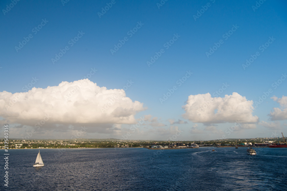 Coast of Bridgetown, Barbados seen from Caribbean sea. Sailing ships in Caribbean sea. Summer vacation on Caribbean tropical island. Idyllic seascape on blue sky with clouds. Caribbean wanderlust