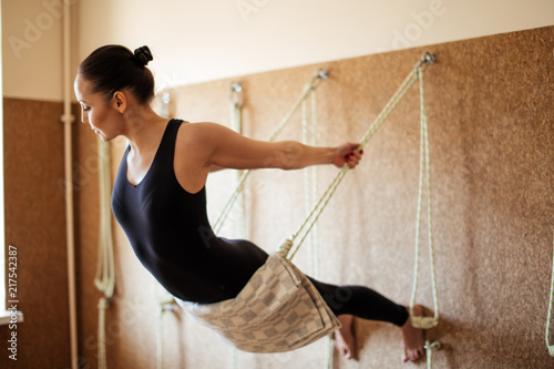 Photos young woman is performing the yoga exercise on the ropes