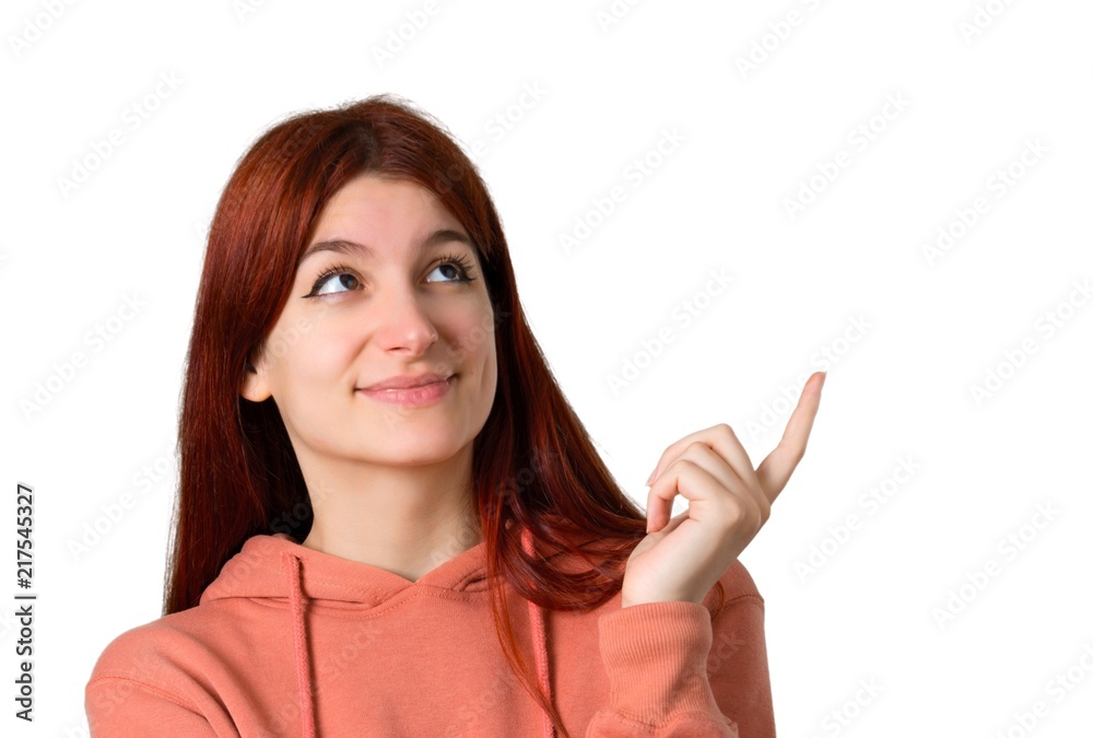 Young redhead girl with pink sweatshirt pointing with the index finger a great idea and looking up on isolated white background Young redhead girl with pink sweatshirt pointing with the index finger a great idea and looking up on isolated white background
