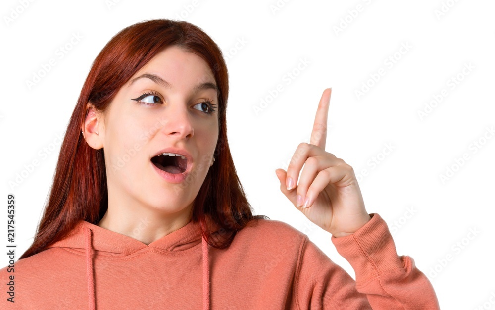 Young redhead girl with pink sweatshirt intending to realizes the solution while lifting a finger up on isolated white background Young redhead girl with pink sweatshirt intending to realizes the solution while lifting a finger up on isolated white background