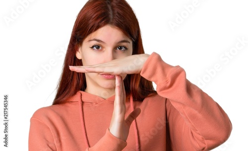 Young redhead girl with pink sweatshirt making stop gesture with her hand to stop an act on isolated white background