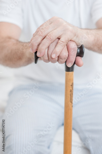 Hands of an old senior man on a cane
