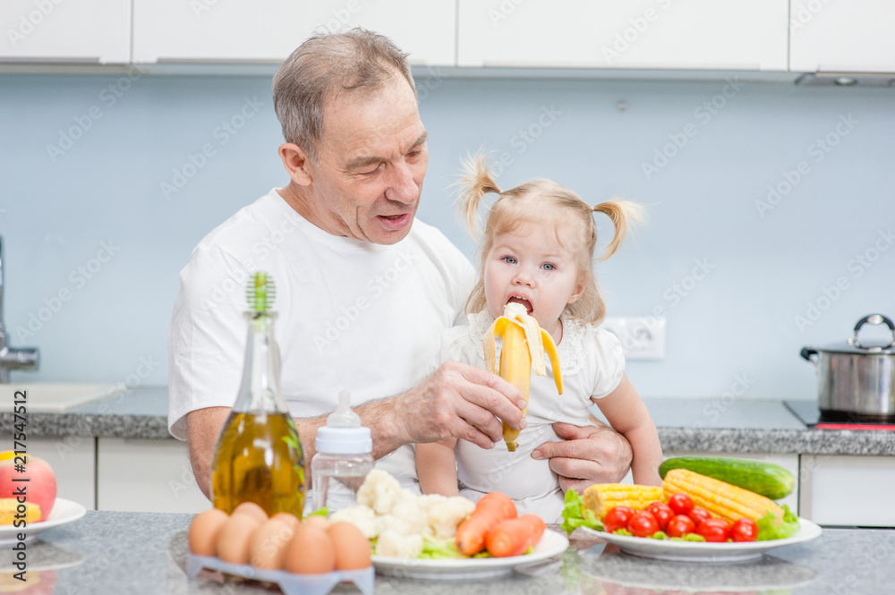 grandfather feeding her granddaughter with a banana grandfather feeding her granddaughter with a banana