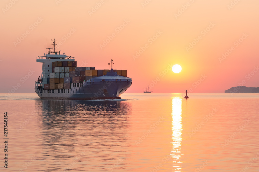 Containerschiff läuft bei Sonnenaufgang in den Hafen ein