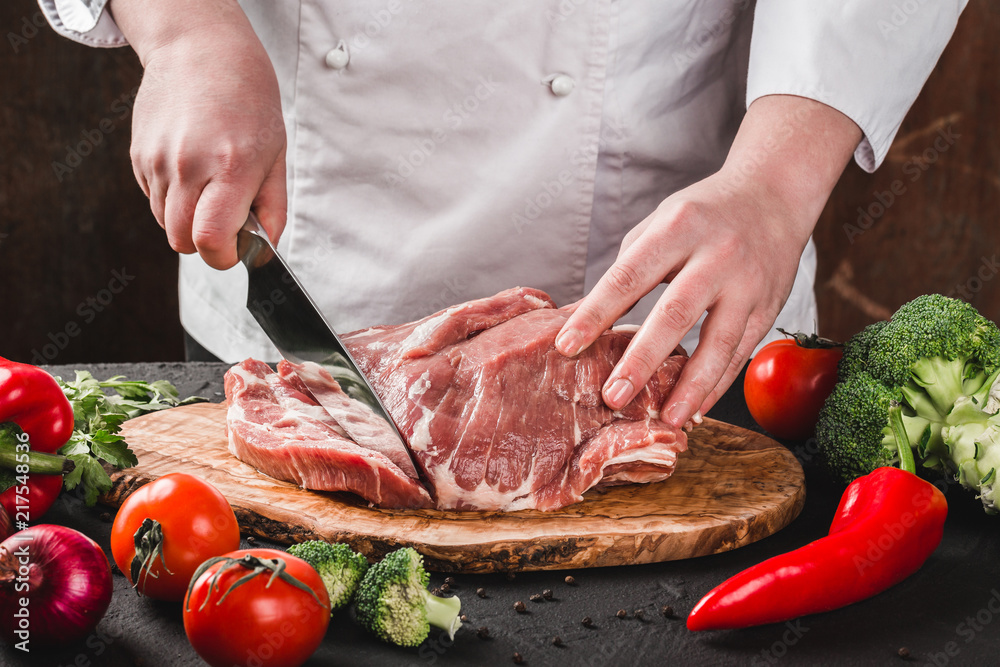 Chef Butcher cutting pork meat with knife on kitchen, cooking food