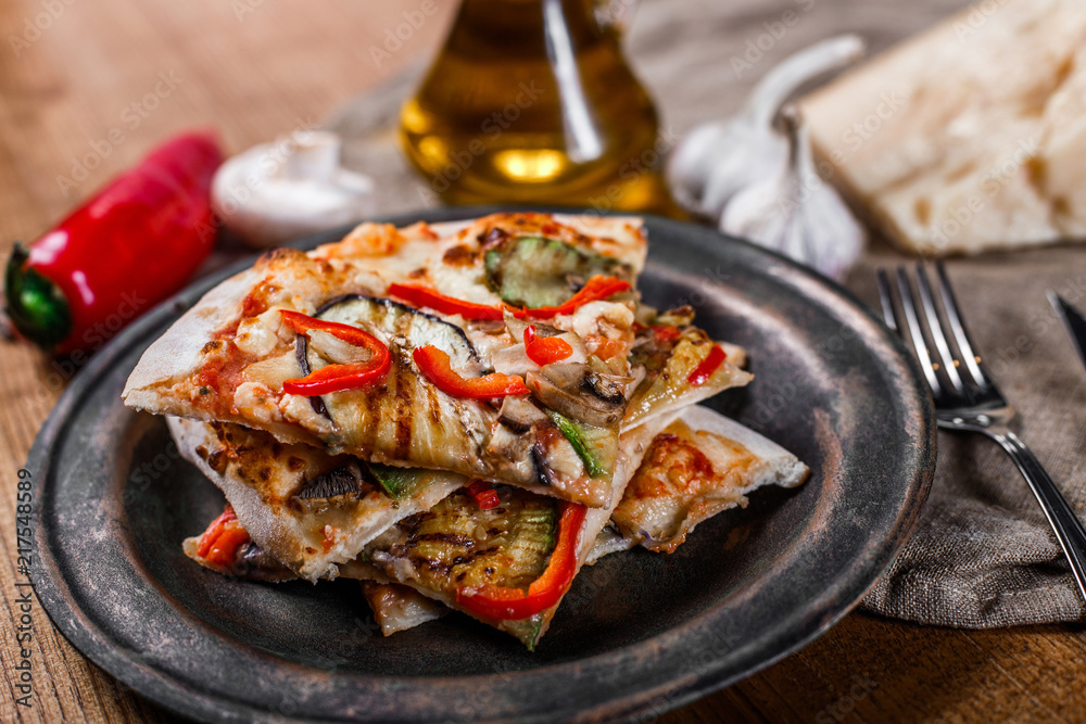 Sliced pizza with chicken, zucchini, eggplant, pepper, cheese and mushrooms on the plate vintage. Top view. Toning Sliced pizza with chicken, zucchini, eggplant, pepper, cheese and mushrooms on the plate vintage. Top view. Toning