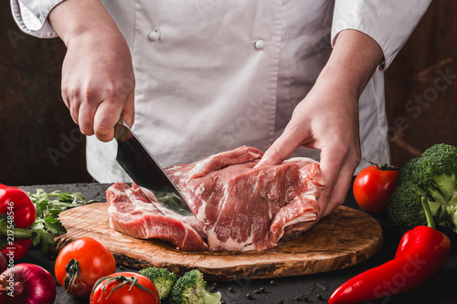 Chef Butcher cutting pork meat with knife on kitchen, cooking food