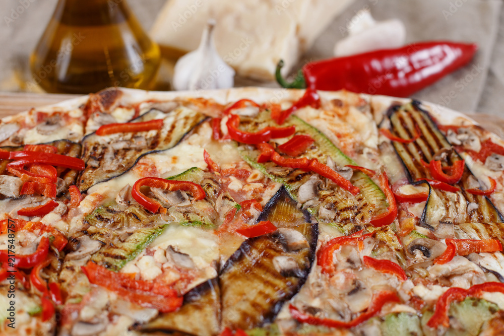 Delicious pizza with chicken, zucchini, eggplant, pepper, cheese and mushrooms on wooden rustic table. Top view. Toning Delicious pizza with chicken, zucchini, eggplant, pepper, cheese and mushrooms on wooden rustic table. Top view. Toning