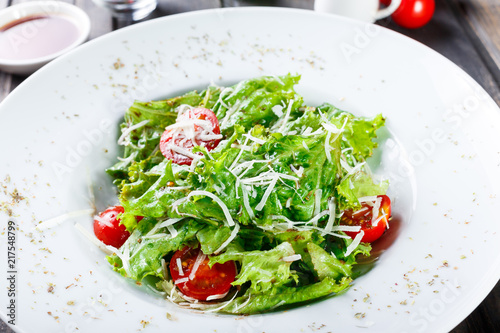 Fresh salad with mixed greens, cherry tomatoes, parmesan cheese on wooden background. Healthy food. Ingredients on table