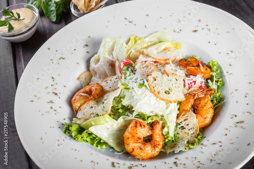 Shrimp salad with parmesan cheese, croutons, tomatoes, mixed greens, lettuce on wooden background. Healthy food