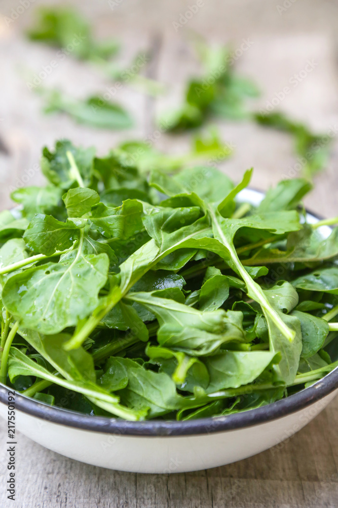 Fresh rucola salad in a bowl on the wooden background Fresh rucola salad in a bowl on the wooden background