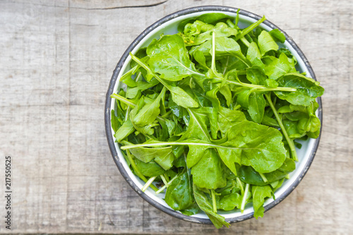 Fresh rucola salad in a bowl on the wooden background