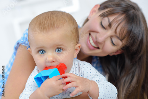 Mother smiling at baby chewing toy