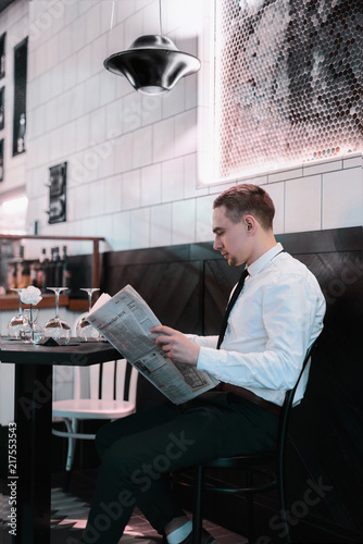 Businessman seating at restourante reading a newspaper photo