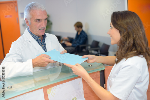 Фотография Doctor handing file to receptionist