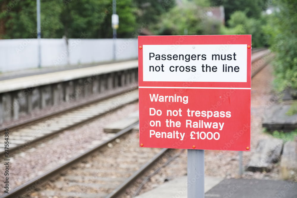 Passenger warning sign at railway train station stating do not trespass or penalty fine will be issued if you cross the rail line