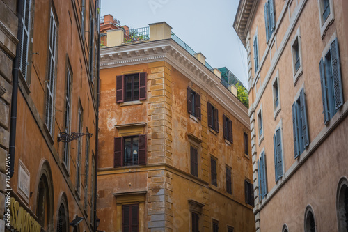 Old tenements in Rome, orange color of facades, windows with shutters 