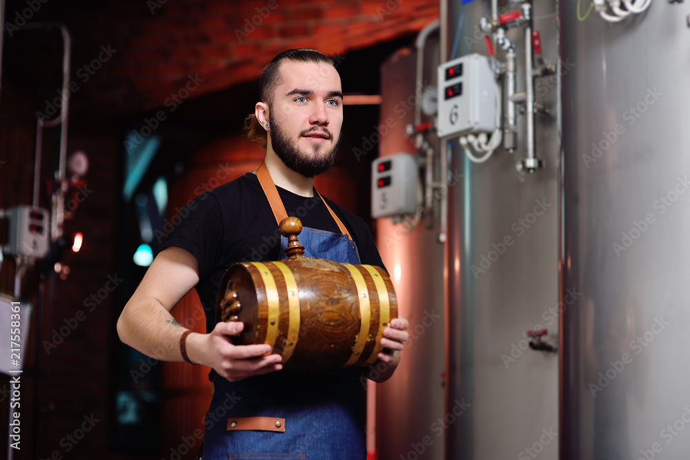 young attractive bearded man with a wooden barrel of wine or beer