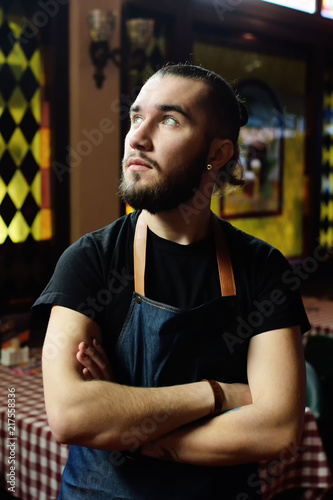 cute bearded male waiter looking in the side on the restaurant background