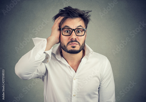 Canvastavla Confused young man holding hand on head